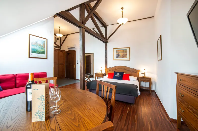 Wnętrze z widocznymi belkami, łóżkiem i czerwoną sofą — Deluxe Premium, Hornigold