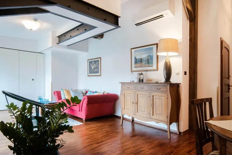 Salon z drewnianymi belkami, czerwoną sofą i komodą — Apartament Hornigold, Hornigold